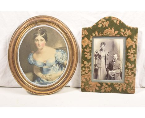 An oval lacquered brass frame containing coloured print of a glamorous young lady, late 19th Century25x22cms, material covere