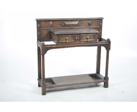 A 1920's oak hall stick standThe glove box with a single drawer, brass droplet handles and moulded embellishments supported o