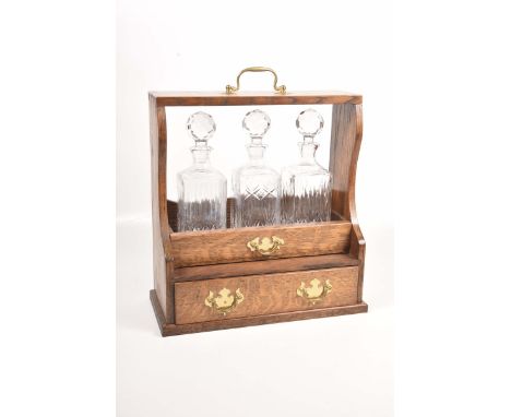 An oak cased three decanter Tantalus, mid 20th CenturyThe Tantalus with oak decanter drawer, with single drawer below, height