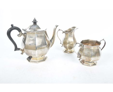 A silver three piece tea service, Sheffield 1951Of octagonal panelled form, the teapot with an ebonised C scroll handle and e