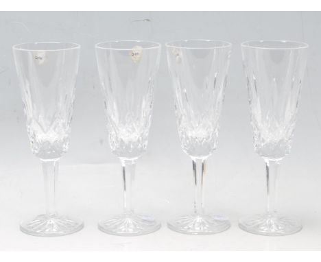 A set of four Lismore pattern Waterford crystal champagne flute glasses having geometric lattice decoration. Comes boxed. Com