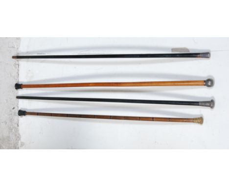 A group of four early 20th century wooden shaft walking sticks. Two working sticks with black ebonised shafts and silver Hall