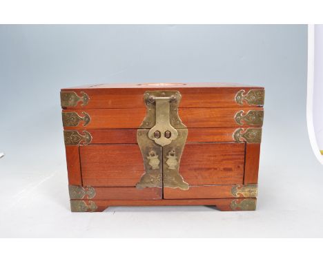 A vintage 20th century Chinese hardwood jewellery box having geometric patterns to the lid opening to reveal a fully appointe