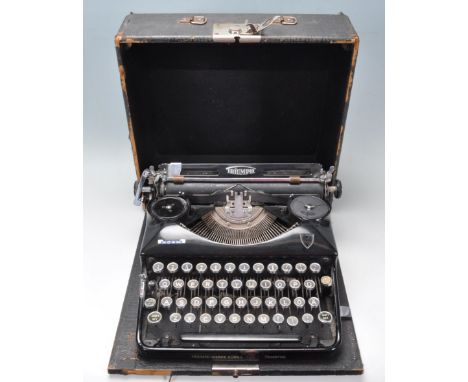 A vintage Triumph Norm German typewriter having a black body with qwerty keyboard with German lettering, set within a black l