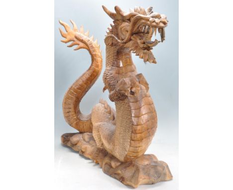 A vintage 20th century Chinese dragon having a natural finish with stylised decoration raised on a naturalistic base. Measure