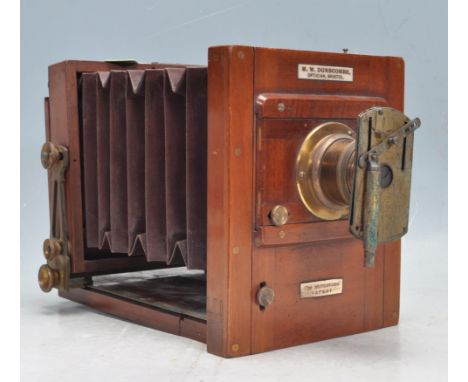 An antique early 20th century mahogany and brass bound half plate field camera by J Lancaster &amp; Sons. The camera having a