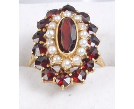 An 18ct gold ring with layered with rows garnets and seed pearls having a central garnet cabochon with seed pearl and circula