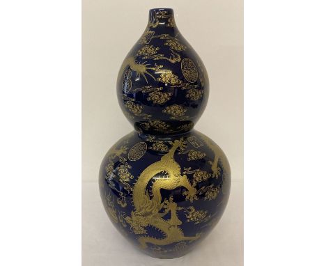 A large ceramic, bottle gourd shaped vase. Deep blue glaze with gilt dragon and symbol detail. Signed to underside. Approx. 4