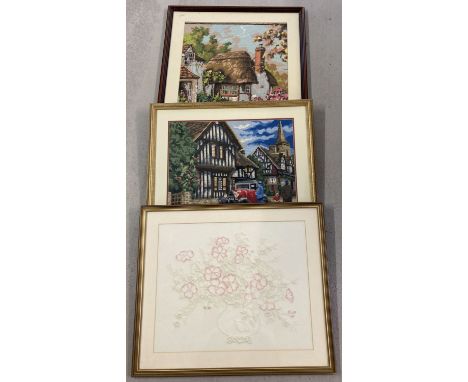 3 framed and glazed tapestry and embroidered pictures. Depicting flowers and traditional cottages. Largest frame size 76cm x 