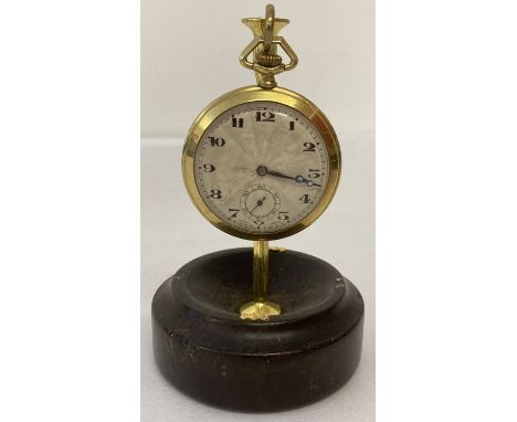 A vintage gold filled pocket watch with engine turned detail to face and back of case. Together witha wooden based stand. Wor