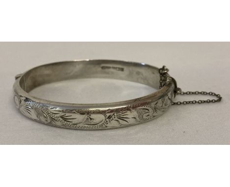 A vintage silver hinged bangle to half floral engraving decoration. Complete with safety chain. Hallmarked Birmingham 1970. T