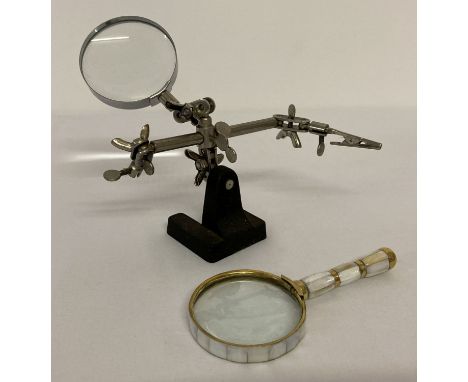 A vintage desk top adjustable magnifying glass. Together with a brass and pearl handled magnifying glass.