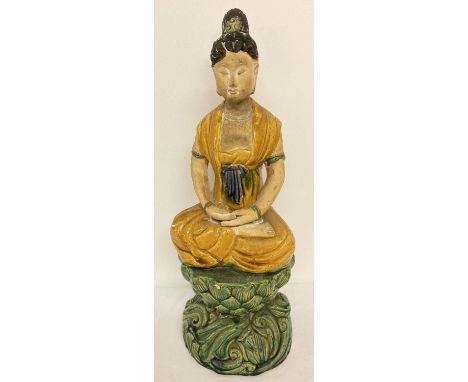 A large partly glazed Chinese stoneware ceramic figurine of a girl sitting atop a lotus flower. With yellow, green and blue g