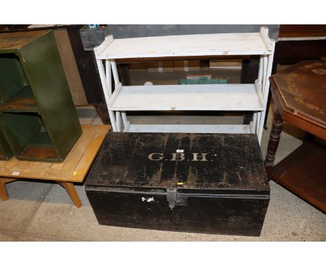 A metal trunk together with a white painted three tier shelving unit