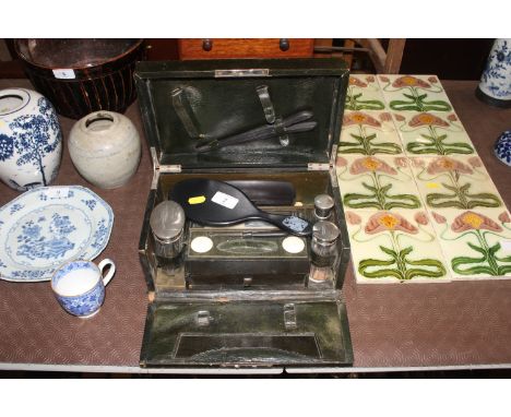 A vanity case and part contents containing dressing table jars, ebony dressing table hand mirror, brush, glove stretchers etc