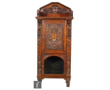 A Victorian carved oak floorstanding cabinet enclosed by an a carved acanthus panelled door below a gallery shelf over an arc