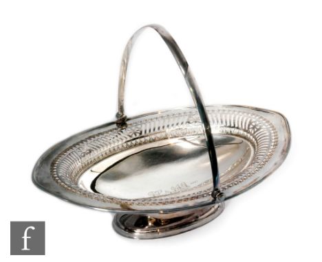 A hallmarked silver oval pedestal bread basket of plain form with pierced border below swing handle, engraved initials to cen