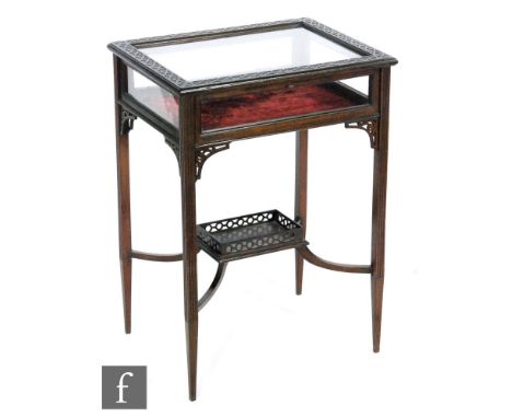 An early 20th Century bijoiterie table or vitrine of rectangular form, the hinged top with a blind fret-carved border over fr