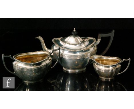 A hallmarked silver three piece boat shaped tea set detailed with a reeded frieze below gadroon borders, engraved initials an