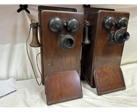 Two wooden cased wall mounted telephones, with mouth piece to the left hand side, crank handle to the right hand side, two be