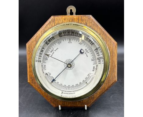 Ships brass cased circular barometer on an octagonal oak plaque.  Barometer face 16cm. Plaque 25cm. 
