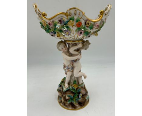 A Meissen table centrepiece with a pierced twin-handled basket, a supporting column with two putti on a rocky base and floral