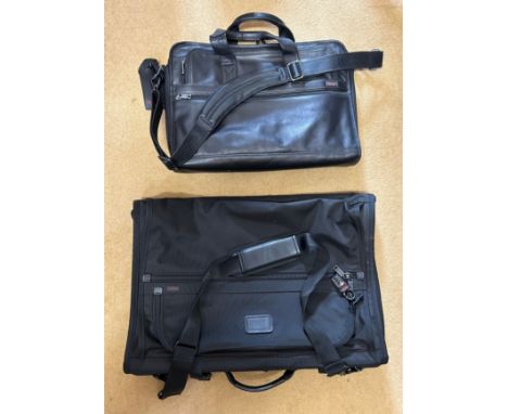 A Tumi black leather briefcase/laptop bag together with a black Tumi suit carrier with leather handles. 