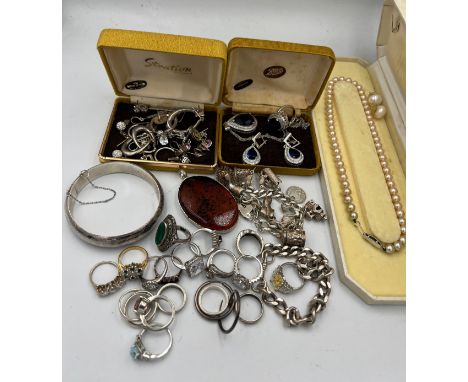 A large quantity of mainly silver jewellery to include charm bracelet, watch chain, bangle, rings and a faux pearl necklace. 