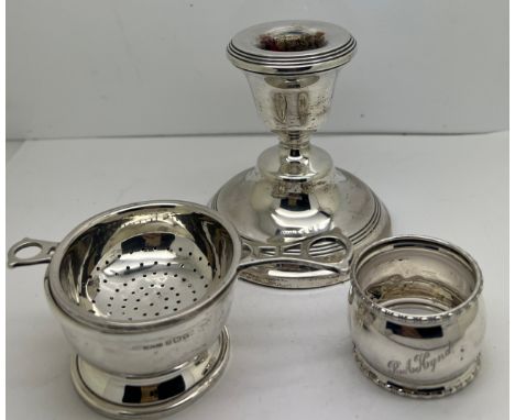 Silver to include tea strainer on bowl, napkin ring and a candlestick with weighted base. Various dates and makers. Weight of