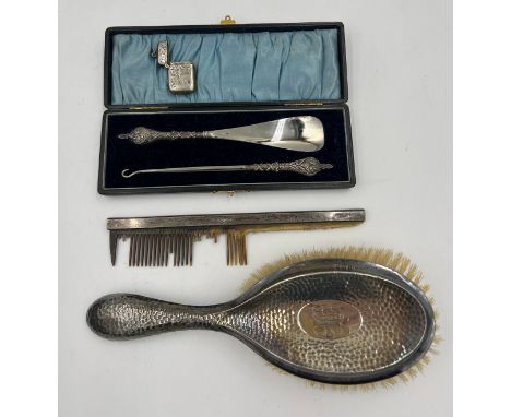 A boxed silver handled shoe horn and button hook, a silver backed hairbrush and comb together with a small silver vesta case 
