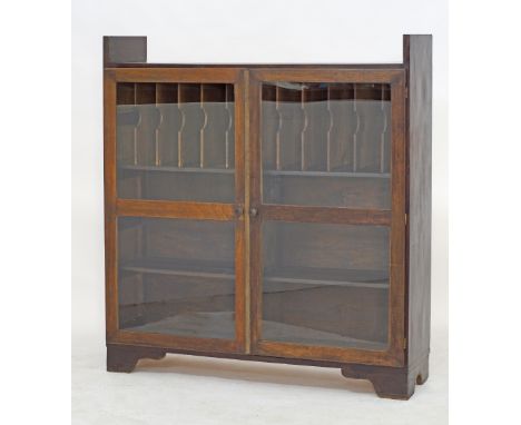 A stained plywood bookshelf unit, the first compartment with vertical divisions to take magazines, with two glazed doors, on 