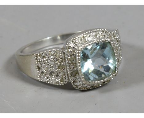 A 9 carat white gold ring set with an aquamarine and diamonds on pierced shoulders, size K.