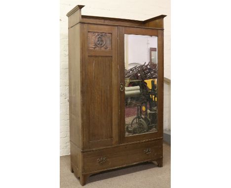 A panelled oak Arts and Crafts mirror fronted double wardrobe raised on bracket feet.