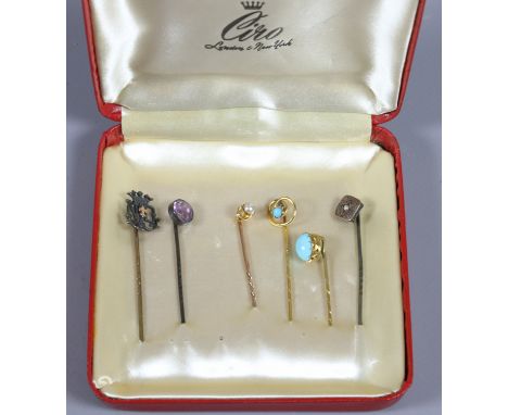 A case containing six stick pins to include gold examples, turquoise, pearl and amethyst.