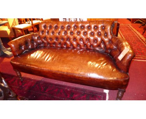 A Victorian sofa of smaller proportions upholstered in buttoned tan leather with studded detail raised on turned support sand