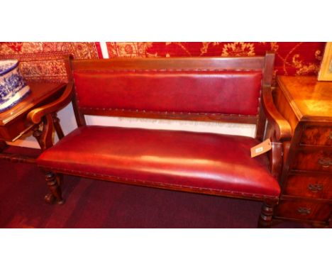 A Victorian mahogany hall bench upholstered in red faux leather on turned supports 