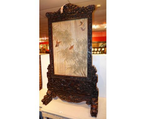 A Chinese rosewood table screen with ornately carved panels and feet, having a removable screen tapestry with Chinese imagery