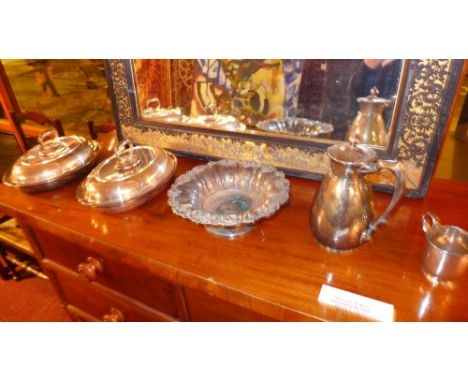 A pair of silver plated lidded serving dishes, a silver plated ornate fruit bowl, a claret jug and a mug 