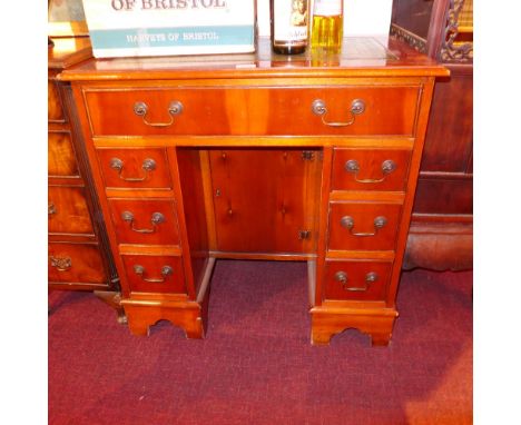 A small yew wood kneehole desk with lined top above seven drawers on bracket feet