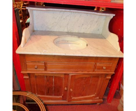 A marble and pitch pine washstand, having an inset porcelain basin over two short drawers and two cupboard doors