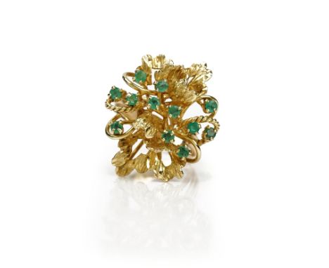 A gold and emerald ring, in an abstract design, claw set with twelve small circular cut emeralds, detailed 14 K, ring size R,