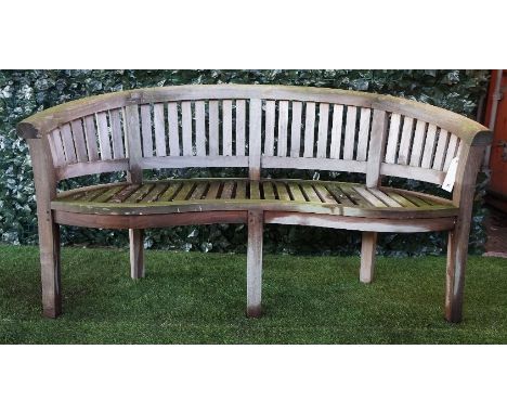 A teak framed semi-elliptic garden bench with slatted back and seat, on block supports, 161cm wide x 85cm high. 