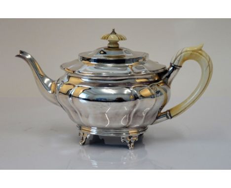 A silver teapot, of panelled oval form, raised on three feet, with an ivory handle and finial to the hinged lid, London 1902,