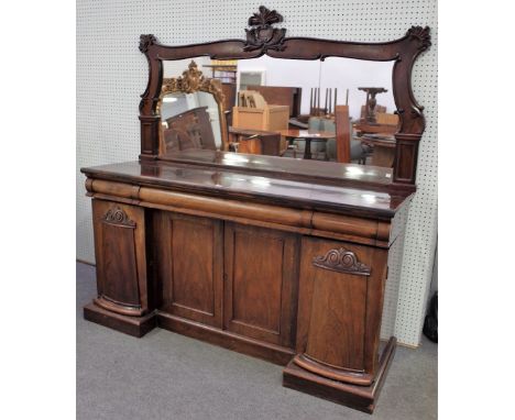 An early Victorian rosewood sideboard, with a foliate and scroll carved mirror back, three frieze drawers above an inverted b