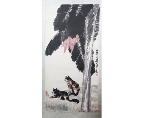 A Chinese hanging scroll, 20th century, ink and colour on paper, painted with two cats beneath an overhanging plaintain tree,