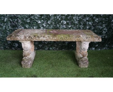A reconstituted stone garden bench on serpent trestle supports, 130cm wide, together with a similar on scroll supports, 101cm