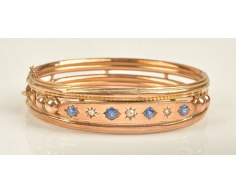 A late Victorian 9ct gold, sapphire and diamond set oval hinged bangle, mounted with four sapphires alternating with three di