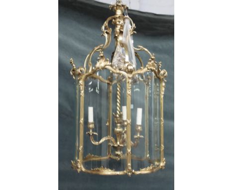 A gilt brass hexagonal hall lantern, in the Louis XV style, 20th century, with serpentine glazed panels and internal three li