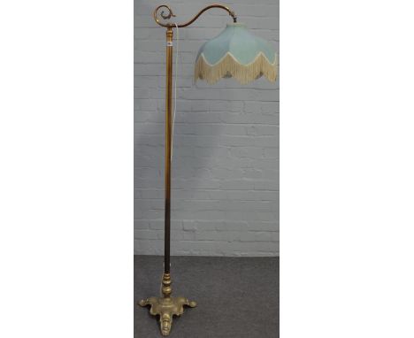 An early 20th century brass standard lamp, raised on a triform base with paw feet, with shade, 168cm high Condition Report We