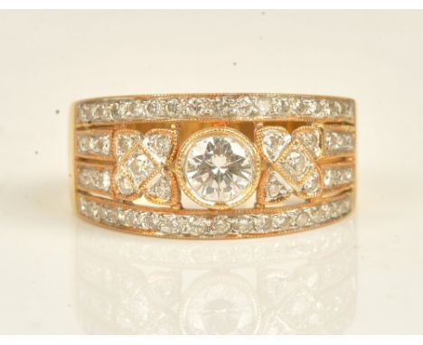 A gold and diamond ring, in a pierced panel shaped design, mounted with circular cut diamonds and with the principal diamond 